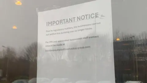 Mick Lunney/BBC A sheet of white paper taped to the inside of a glass door or window. The notice is printed in large text at the top with the heading “IMPORTANT NOTICE”, followed by smaller text explaining that, due to regulatory matters, the businesses operating from the building can no longer trade. The sign also provides an email address for staff from PM Law and associated businesses to contact.