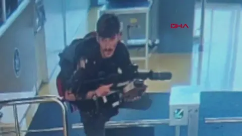 AP One of the suspects pictured on CCTV climbing over a turnstile holding a gun at the entrance of Turkish Aerospace Industries' headquarters