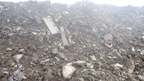 EA A close up of the pile of rubbish which had been dumped. Dirt, concrete blocks and sticks can be seen piled high.