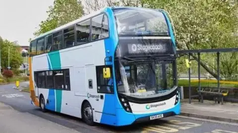 Stagecoach A blue and white Stagecoach double decker bus parked at a bus stop with a driver in the front seat.