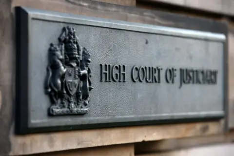 A metal sign on the wall of the High Court in Edinburgh which reads High Court of Justiciary