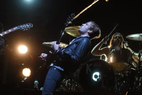 Caleb Followill of Kings of Leon leans back while playing a guitar solo at the Glastonbury festival  