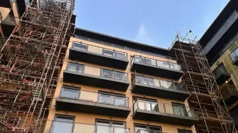 Inside the inner circle of the Mosaic apartment where extensions and construction site is still shown. A number of balconies can be seen on the upper floors of the building with scaffolding down each side where work is continuing.