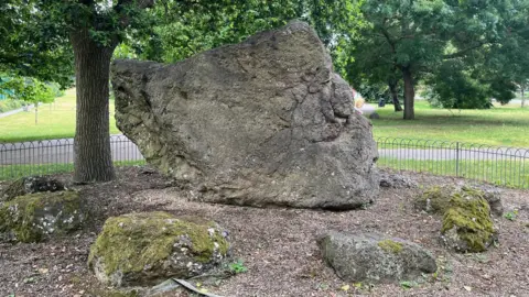 BBC/Joshua Askew A large rock with smaller rocks place around it. The big rock looks eerily like it has a human face. 