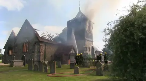 A fire on the roof and inside the church with black smoke pouring in the sky