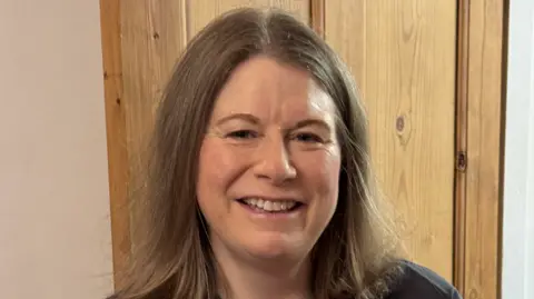 Victoria Wheatley A woman with shoulder length brown hair smiles.