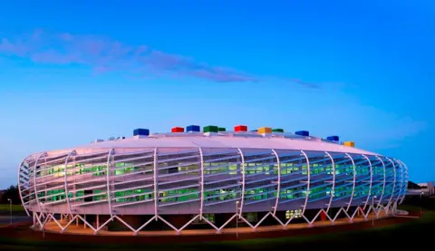 BBC Monkseaton High School. It is a colourful, oval-shaped futuristic-looking building with multi-coloured bricks on its roof.