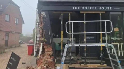 East Sussex Fire and Rescue Service The front of a severely damaged coffee shop. Bricks have fallen from the side of the building and there is a building support equipment positioned at the front of the shop.