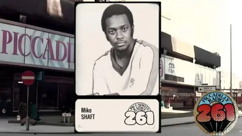 Captura de pantalla de la tarjeta de presentador de Piccadilly Radio de Mike Shaft en Piccadilly. Mira a la cámara y viste un jersey blanco de cuello en V.