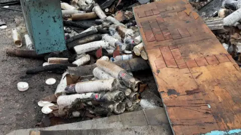A pile of rubble including doors and paper cups.