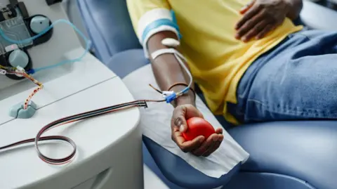 Man holding soft ball and donating blood at center - stock photo
