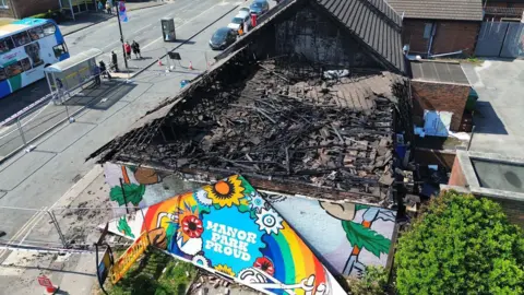 supplied A drone shot showing the side of a block of shops destroyed by fire.