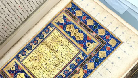 Cambridge University Library An open 16th Century book showing a writing on gold edged with bright blue, red, black and pink decorations Rawḍat al-ṣaffāʾ (Garden of Purity) by Muḥammad bin Khāwand Shāh