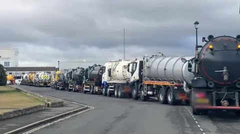 At least nine tankers parked nose-to-tail on a road