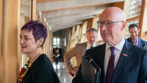 PA Media Angela Constance and John Swinney walking into the chamber at the Scottish Parliament
