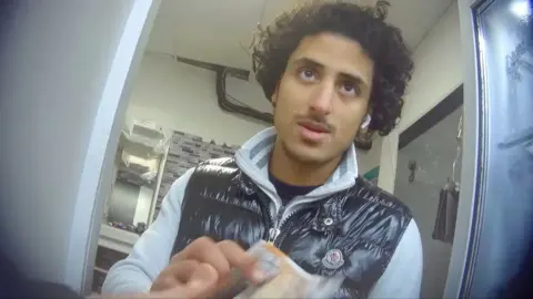 Man with black curly hair and thin moustache accepting money