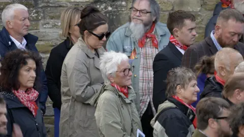 Mourners at the funeral of Dewi Morris, many wearing red-and-white neckerchiefs