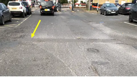 Dennis Sherwood Station car park with uneven surfaces- cars parked on either side 