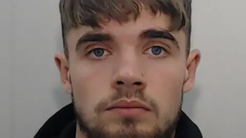 Greater Manchester Police A police mugshot of 22-year-old Jack Marsden Marr. He has blue eyes, a short beard and a nose stud.