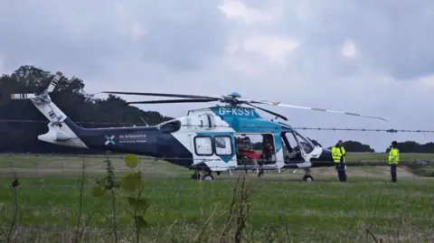 Eddie Mitchell A blue and white air ambulance sits on a field