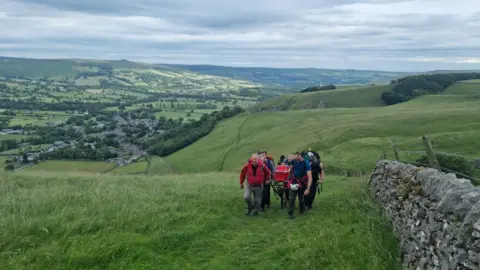 Edale Mountain Rescue Team Rescuers with injured woman in stretcher near Winnats Pass in Peak District