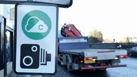 Getty A road sign displaying a clean air zone area with a camera underneath it. Foreground is a commercial vehicle on a road