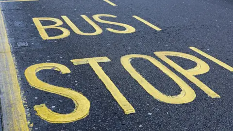 The words bus stop are painted in yellow on a road.