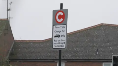 A grey and white road sign saying motorists can pay the fee "on line", instead of "online"