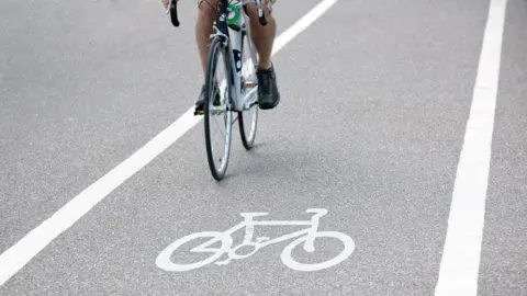A stock image of a person riding a bicycle over a bike path symbol. 