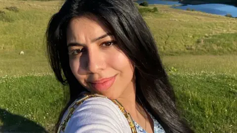 Maariya Kahn is standing in a field on a summer's day as she smiles at the camera for a selfie. 