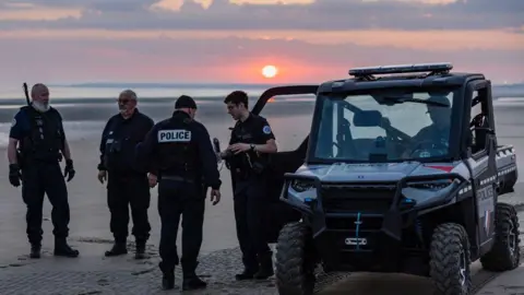 Getty Images Polisi berjaga di sebuah pantai di Prancis, berupaya menghentikan migran yang menyeberang dengan perahu kecil