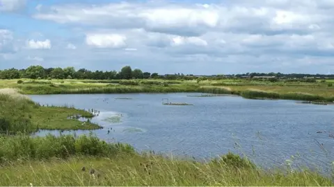 North Cave Wetlands with a lake surrounded by grassland