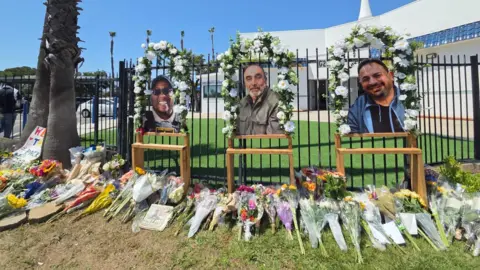 Dozens of flower bouquets line the sidewalk outside the fence of the Islamic Center of San Diego, where the images of three victims - Amin Abdullah, Mansuor Kaziha and Nadir Award are placed with flowers around them.