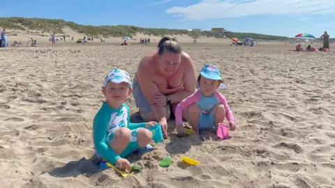 Woman and two children sat on the sand 