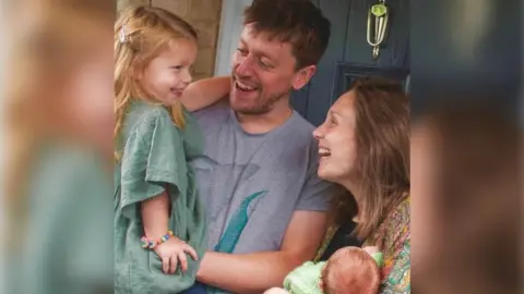 Family picture man and partner with each person holding a young child