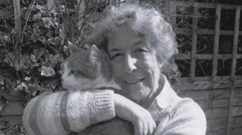 Miles Bingham A black and white photograph of an elderly woman holding a cat.