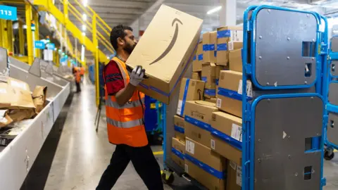 An employee places an item in to a distribution cage at the Amazon LCY3 fulfillment center in Dartford, UK, on , 7 July 7, 2023.