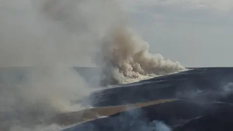 An image of a large amount of white smoke rising from a moorland which is on fire in West yorkshire.