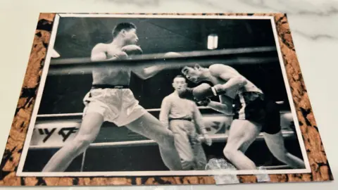 Foto hitam-putih dua petinju bertarung di atas ring