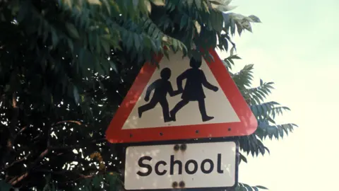 BBC A traffic sign with two children crossing and the word "School".