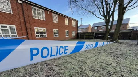 Police tape around a building on a frosty day