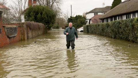 A man wades through floodwaters after the Thames overtopped its banks this winter