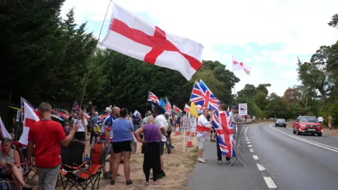 PA Media Protesters with St George's Flags and Union Jacks stand beside a road.