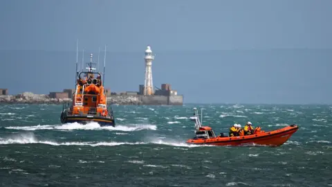 Two RNLI lifeboats travelling on the sea.