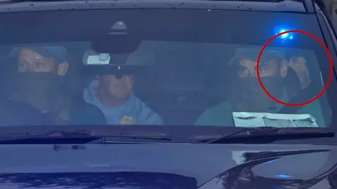 Daniel Kinahan, partially visible in the back of a police car, highlighted in a red circle.