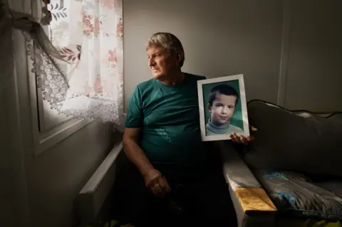 Petro Sereda holding a framed picture of his son Artym.