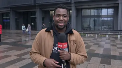 Terel Edmunds holds a microphone on a wet Cardiff street