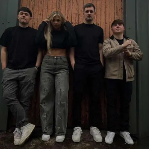 Socialites The members of the four-piece band - three young men and a young woman - stand together in front of a wooden door.