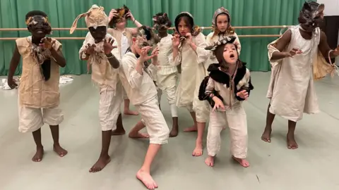 A group of children, dressed in costume and posing as wild animals, pull faces for the camera