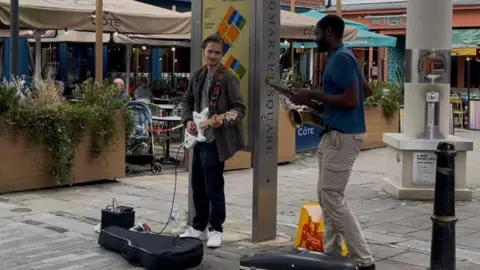 Megan Shaw/LDRS Two buskers, one playing an electric guitar and one playing a saxophone.